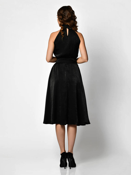 Young beautiful woman posing in new dark black fashion winter dress backside rear view - 写真・画像
