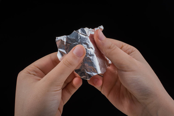 Hand zerreißt eine herzförmige Aluminiumfolie auf einem hölzernen Hintergrund - Foto, Bild