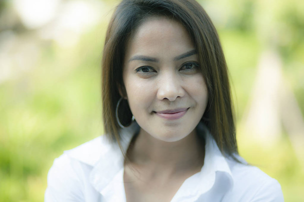 Asya genç kadın dişlek gülümseyen yüz yeşil doğal arka planı kapat - Fotoğraf, Görsel