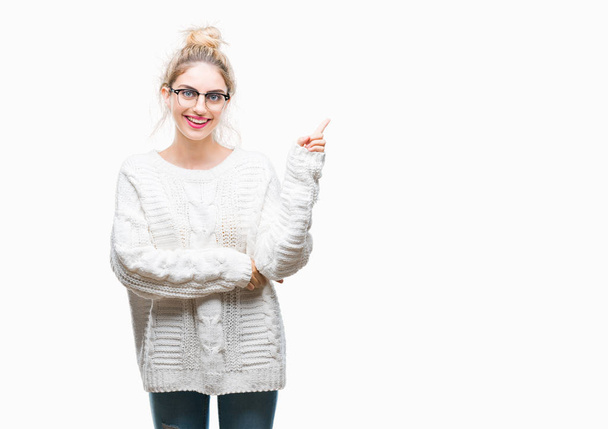 Young beautiful blonde woman wearing glasses over isolated background with a big smile on face, pointing with hand and finger to the side looking at the camera. - Photo, Image
