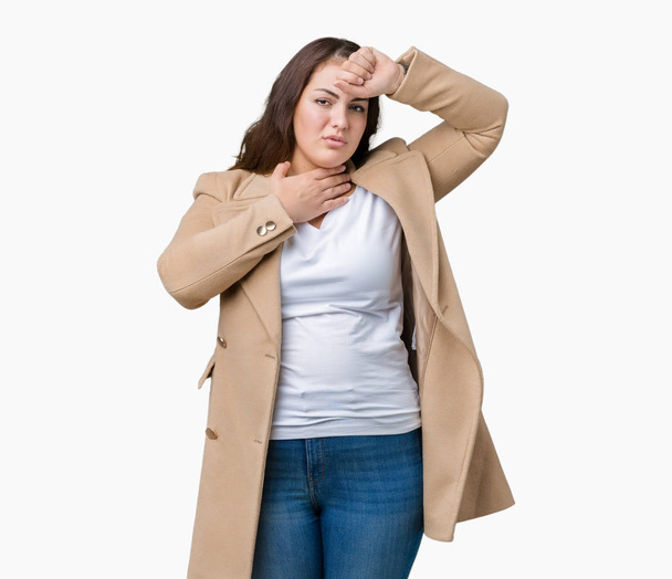 Όμορφη συν μέγεθος νεαρή γυναίκα φοράει παλτό χειμώνα πάνω από απομονωμένες φόντο αγγίζοντας το μέτωπο για την ασθένεια και πυρετό, γρίπη και κρύο, ιού άρρωστος - Φωτογραφία, εικόνα