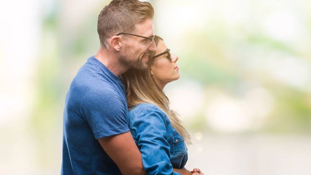 junges verliebtes Paar trägt Sonnenbrille über isoliertem Hintergrund mit Blick zur Seite, entspannte Profilpose mit natürlichem Gesicht mit selbstbewusstem Lächeln. - Foto, Bild
