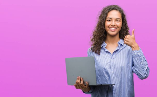 Ok işareti, başparmak ile parmak, mükemmel işareti yapıyor kocaman bir gülümseme ile bilgisayar dizüstü mutlu tutan genç İspanyol kadın - Fotoğraf, Görsel