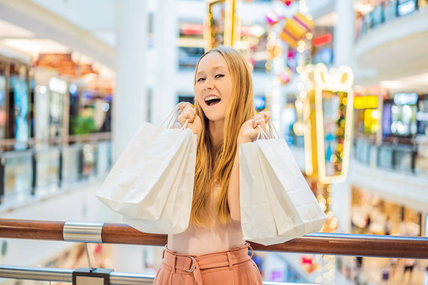 Young woman with Christmas sale purchases in new year decorated mall. - Fotoğraf, Görsel
