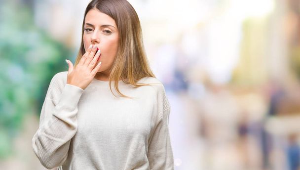 Молодая красивая женщина случайный белый свитер на изолированном фоне скучно зевая усталый покрывающий рот рукой. Беспокойство и сонливость
. - Фото, изображение