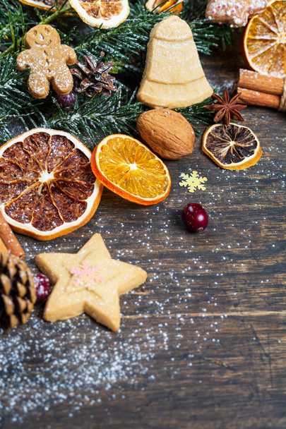Christmas background with green Christmas tree branch, festive decoration, dry fruits, home made cookies and traditional seasonal spices, top view, vertical composition - Φωτογραφία, εικόνα