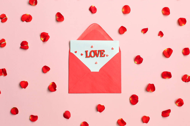 Enveloppe pétales de rose et coeurs rouges sur fond rose. Saint Valentin
 - Photo, image