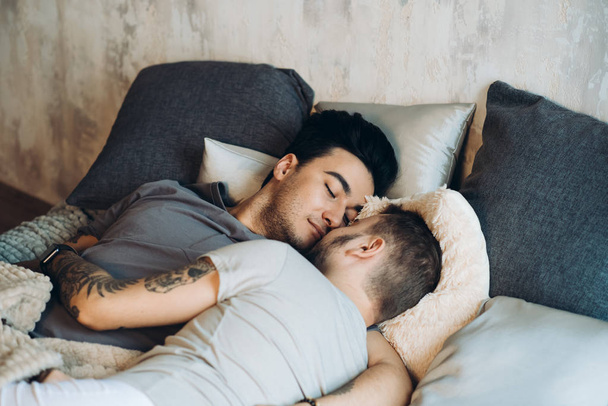 A homosexual couple on bed in studio with loft interior - Zdjęcie, obraz