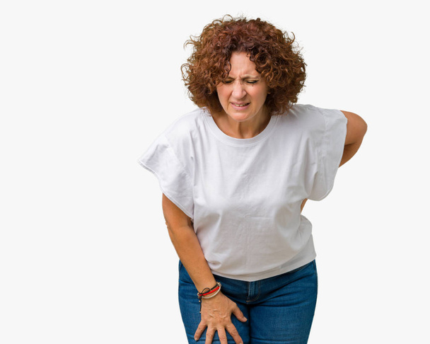 Hermosa mujer de mediana edad ager vistiendo camiseta blanca sobre fondo aislado Sufrimiento de dolor de espalda, tocando la espalda con la mano, dolor muscular
 - Foto, imagen