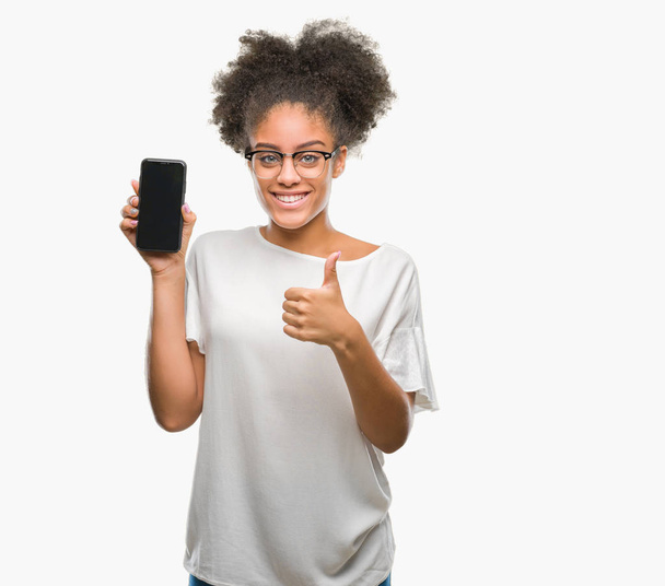 Joven hermosa afroamericana mostrando la pantalla del teléfono inteligente sobre fondo aislado feliz con una gran sonrisa haciendo signo ok, pulgar hacia arriba con los dedos, señal excelente
 - Foto, Imagen