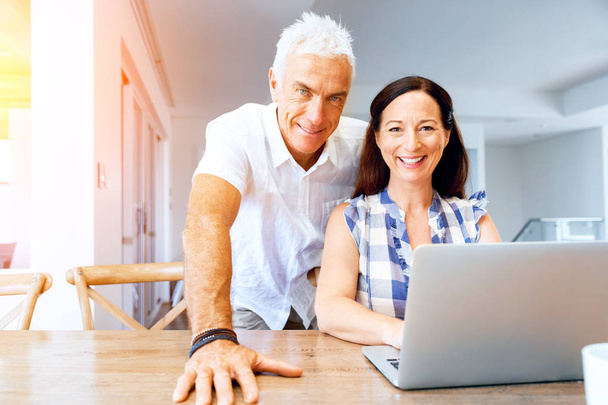 Счастливая современная зрелая пара работает над ноутбуком дома
 - Фото, изображение