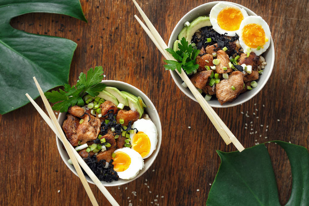 two poke bowl of fried rice, chicken fillet and eggs on wooden table - 写真・画像