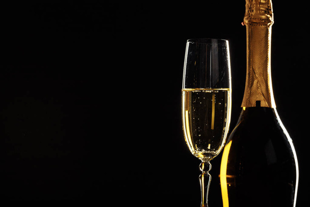 bottle of champagne and glass over dark background - Foto, Imagen