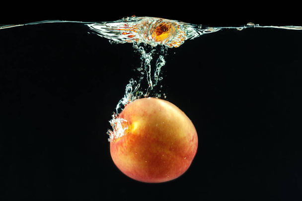 Peach dropped into water with bubbles - Fotografie, Obrázek