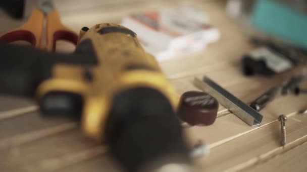 Gele automatische schroevendraaier, nagels, nietjes, metalen gereedschappen op tafel geplaatst - Video