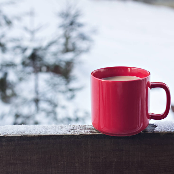 Cup with coffee, tea on the background of the winter landscape.  A cup with a hot drink on the background of the winter forest. the table outdoor in the winter. Winter time concept. - Photo, image