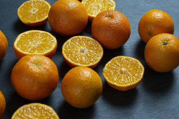 A lot of sliced and whole mandarins on a black background. - Photo, Image