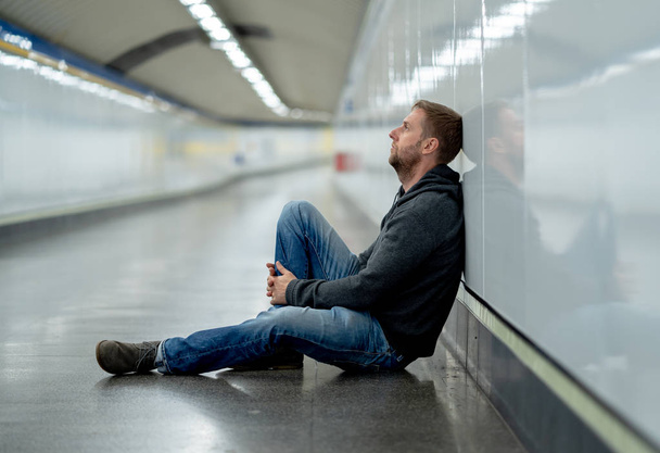 Üzgün genç adam ağlayan acı depresyon stres zemin sokak Metro'ya eğilerek duvar ruhsal bozukluk duygusal ağrı bağımlılığı yalnız ve işsizlik kavramı üzerinde umutsuz seyir üzerinde oturan. - Fotoğraf, Görsel