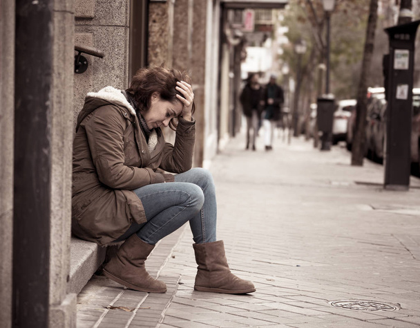 Attractive woman suffering from depression felling sad unhappy heartbroken and lonely sitting in city urban street in Mental health Emotional pain Abusive relationships and loneliness concept. - Foto, Imagem