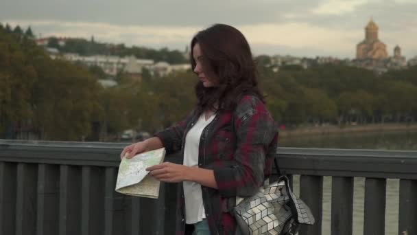 Beautiful young woman with tourist map looking aroung in the city street. - Felvétel, videó