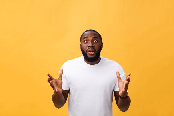 Porträt eines afrikanisch-amerikanischen Mannes mit schockierten und ungläubigen erhobenen Händen. isoliert über gelbem Hintergrund. - Foto, Bild