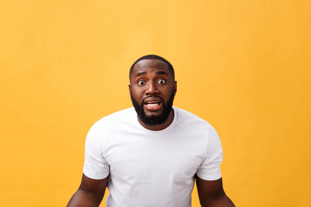 Portrait of african american man with hands raised in shock and disbelief. Isolated over yellow background. - 写真・画像