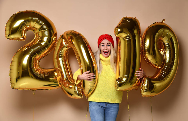 Women celebrating New Year party happy laughing in yellow sweater blouse with 2019 gold balloons  - 写真・画像