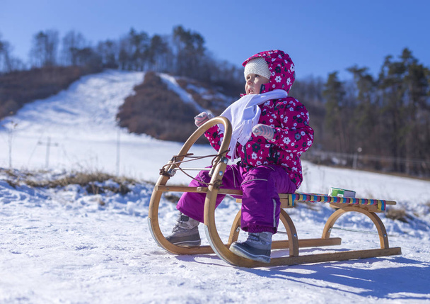 Маленька дівчинка насолоджується катанням на санях. Дитяче катання. Діти грають на свіжому повітрі в снігу. Розваги на відкритому повітрі для сімейних різдвяних канікул
. - Фото, зображення