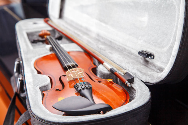 коричнева старовинна скрипка з бантом, що лежить у футлярі крупним планом
 - Фото, зображення