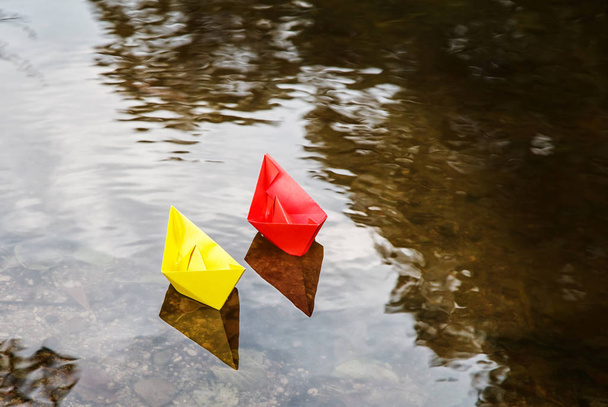 two multicolored paper boats floating on a stream outdoor on autumn day closeup - Photo, Image