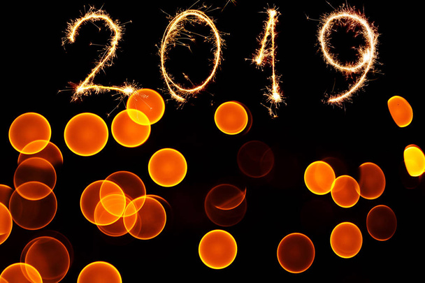 Astract bokeh of christmas lights on black background and sparklers of 2019 year - Φωτογραφία, εικόνα