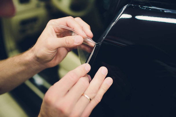 Worker hands installs car paint protection film - Foto, afbeelding