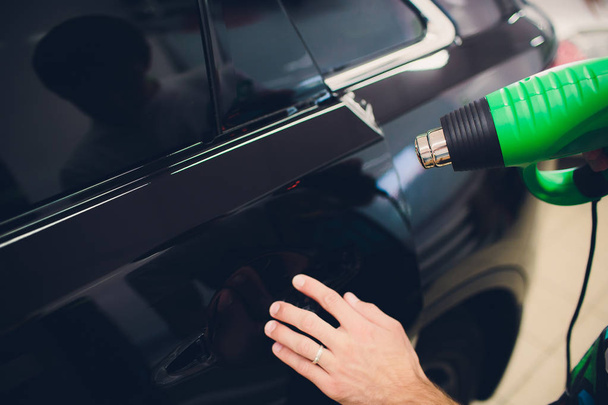 Master installs tint film for car with hairdryer. Concept protection car - Foto, Imagem