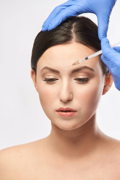 Face needle injection. Young woman cosmetology procedure. Doctor gloves. - Foto, immagini