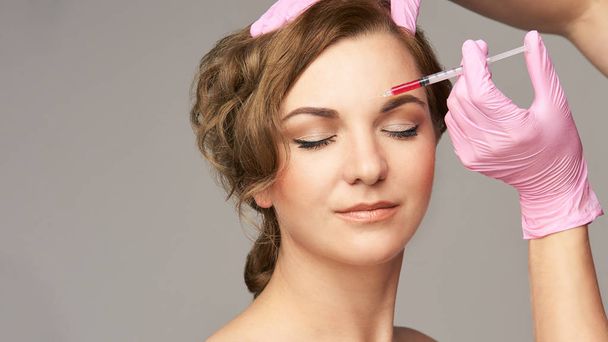 Face needle injection. Young woman cosmetology procedure. Doctor gloves. - Foto, immagini