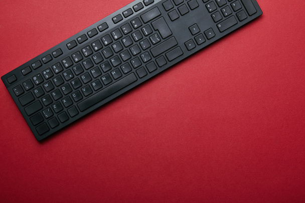 コピーの領域と赤の背景に黒のコンピューターのキーボードの上から見る - 写真・画像