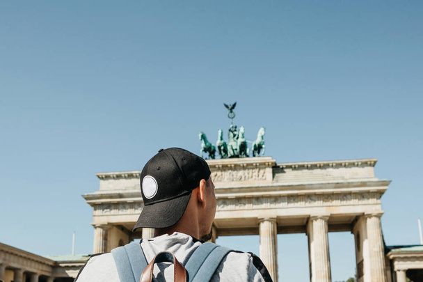 Een toerist of een student met een rugzak in de buurt van de Brandenburger Tor in Berlijn in Duitsland. - Foto, afbeelding
