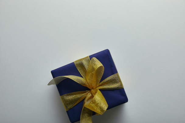 Top view of gift wrapped in blue wrapping paper with yellow ribbon on grey background  - Fotó, kép
