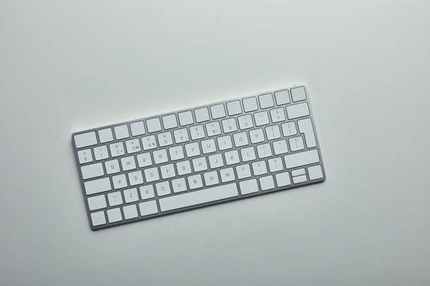 Bovenaanzicht van witte computertoetsenbord op grijze achtergrond  - Foto, afbeelding