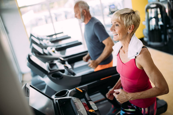 Mature people running in machine treadmill at fitness gym club - Фото, зображення