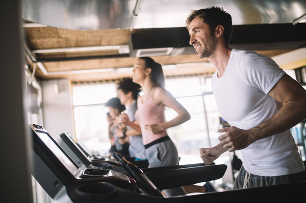 People running on treadmill in modern gym doing cardio workout - Fotó, kép