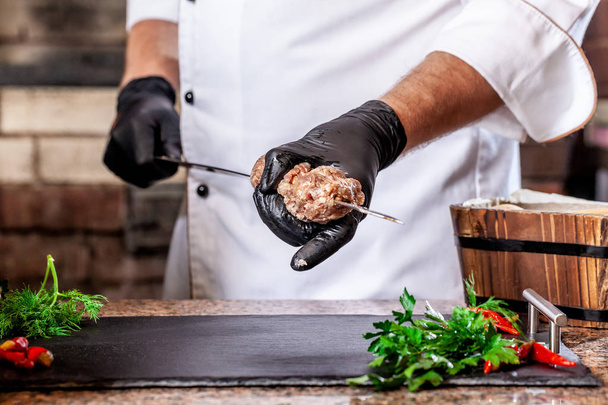 The concept of Georgian cuisine. Recipe for cooking meat lyulya kebab in the dough on the grill. Chef puts meat on a skewer. - 写真・画像