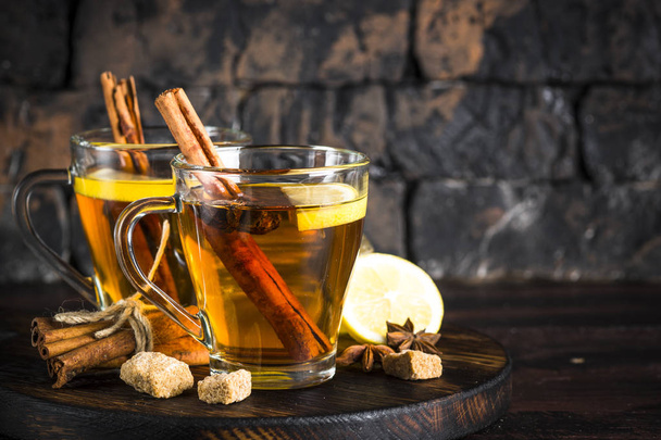 Őszi forró tea, citrom és fűszerek üveg pohár sötét háttér. - Fotó, kép
