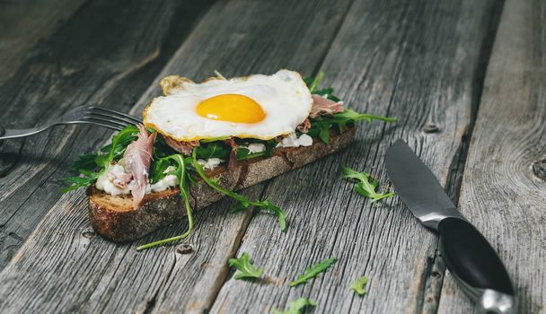 Sandwich with pastors and egg on whole grain bread on old wooden table - Photo, Image