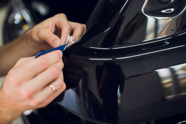 Worker hands installs car paint protection film wrap. - Zdjęcie, obraz