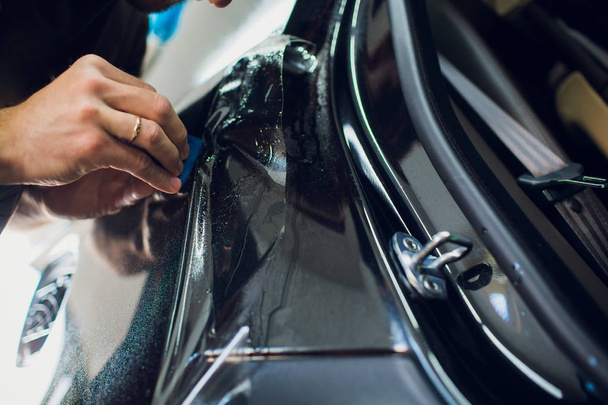 Worker hands installs car paint protection film wrap. - 写真・画像