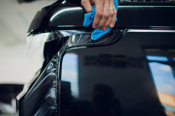 Worker hands installs car paint protection film wrap. - Foto, Bild