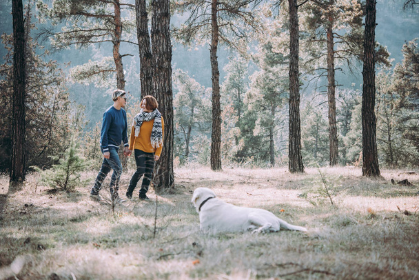 Happy lesbian couple walking in the forest with a dog - Foto, afbeelding