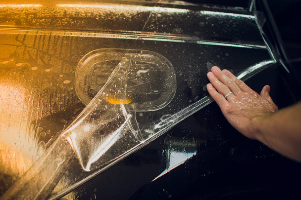 Worker hands installs car paint protection film wrap. - Fotografie, Obrázek