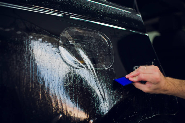 Worker hands installs car paint protection film wrap. - Foto, immagini